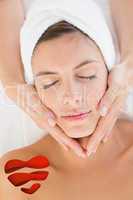 Composite image of attractive woman receiving facial massage at