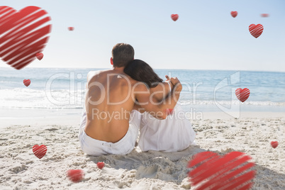 Composite image of couple sitting on the sand watching the sea