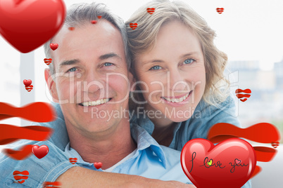 Composite image of smiling woman hugging her husband on the couc