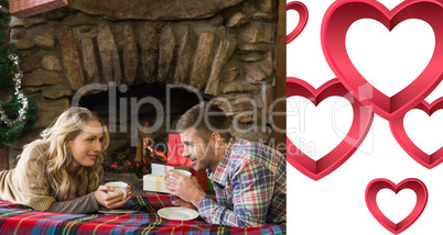 Composite image of couple with tea cups in front of lit fireplac