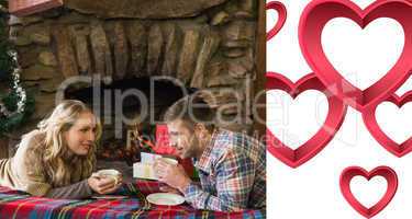 Composite image of couple with tea cups in front of lit fireplac