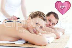 Composite image of smiling young couple having a stone massage