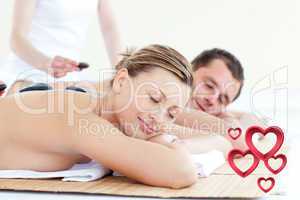 Composite image of young couple having a massage with hot stone