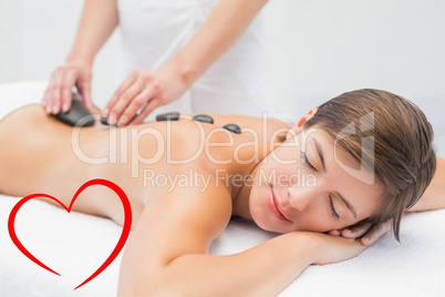 Composite image of beautiful woman receiving stone massage at sp