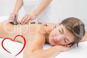 Composite image of beautiful woman receiving stone massage at sp