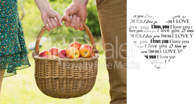 Composite image of basket of apples being carried by a young cou