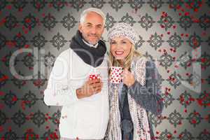 Composite image of happy couple in winter fashion holding mugs