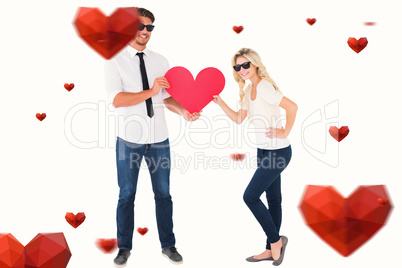 Composite image of cool young couple holding red heart