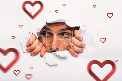 Composite image of young man looking through paper rip