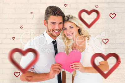 Composite image of attractive young couple holding pink heart