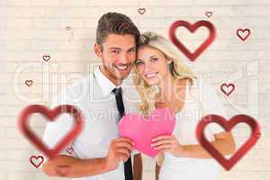 Composite image of attractive young couple holding pink heart