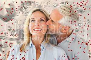 Composite image of affectionate man kissing his wife on the chee