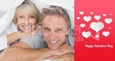 Composite image of couple smiling under the covers