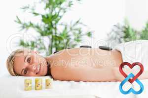 Composite image of blonde smiling woman having a stone therapy