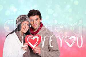 Composite image of young couple smiling holding red heart