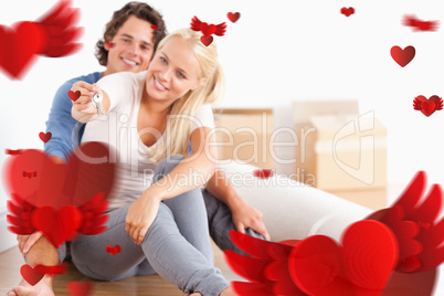 Composite image of woman sitting with her fiance giving keys