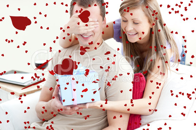 Composite image of smiling woman giving a present to her boyfrie