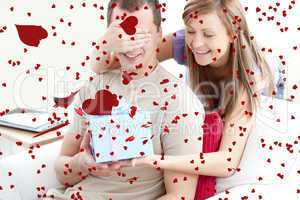 Composite image of smiling woman giving a present to her boyfrie