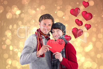 Composite image of couple holding a red heart