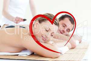 Composite image of young couple having a massage with hot stone