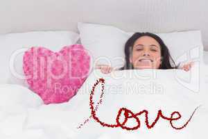 Composite image of woman lying in bed next to a fluffy heart pil