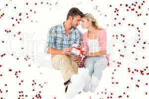 Composite image of attractive young couple sitting holding a gif