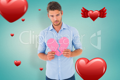 Composite image of sad man holding a broken heart