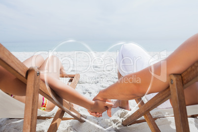 Composite image of couple resting on deck chairs