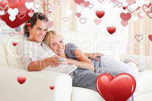 Composite image of couple cuddling while watching tv