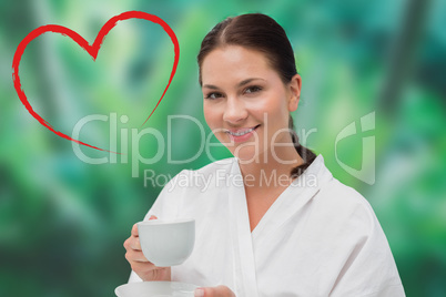 Composite image of beautiful brunette in bathrobe drinking herba