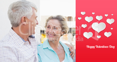 Composite image of happy mature couple sitting on bench in the c