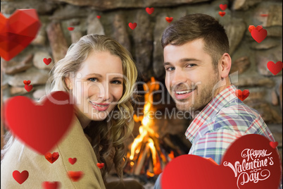 Composite image of smiling young couple in front of lit fireplac