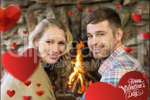 Composite image of smiling young couple in front of lit fireplac