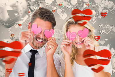 Composite image of attractive young couple holding pink hearts o