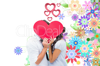 Composite image of couple covering their kiss with a heart