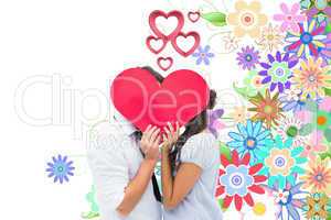 Composite image of couple covering their kiss with a heart