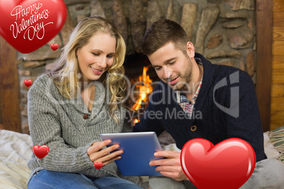 Composite image of couple using tablet pc in front of lit firepl