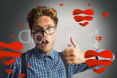 Composite image of geeky hipster covered in kisses