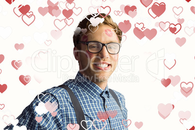 Composite image of geeky hipster covered in kisses