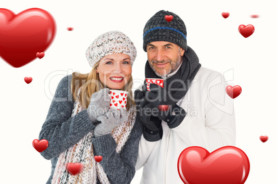 Composite image of happy couple in winter fashion holding mugs