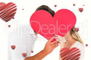 Composite image of attractive young couple kissing behind large