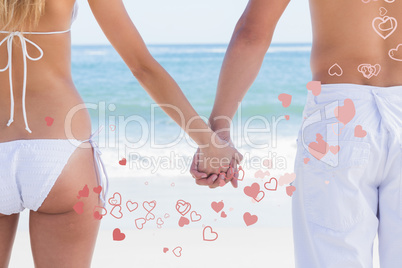 Composite image of young couple in swimwear holding hands