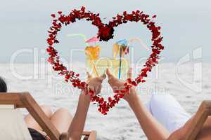 Composite image of couple clinking glasses of cocktail on beach