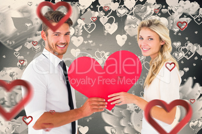 Composite image of attractive young couple holding red heart