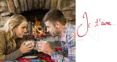 Composite image of couple with tea cups in front of lit fireplac