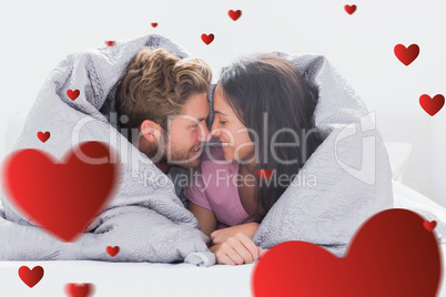 Composite image of couple wrapped in the duvet