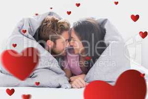 Composite image of couple wrapped in the duvet