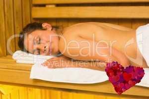 Composite image of happy brunette lying down in a sauna