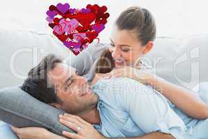 Composite image of cheerful couple relaxing on their sofa smilin