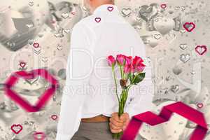 Composite image of man holding bouquet of roses behind back